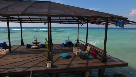 dream-holiday-public-beach-terrace,-wooden-pier-platform-with-balinese-seating,-amazing-sea-view,-shot-from-moving-drone,-gili-trawangan,-bali,-indonesia