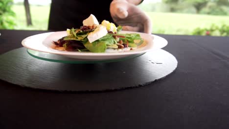 Chef's-hands-putting-dressing-on-salad-while-turning