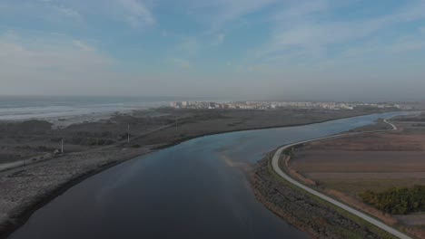 Aerial-view-of-beautiful-river-side-by-side-with-the-ocean-and-crop-fields