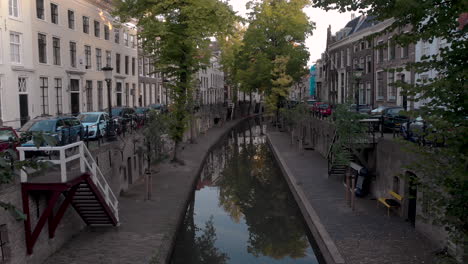 Aerial-early-morning-canal-view-of-the-Nieuwe-Gracht-in-medieval-Dutch-city-of-Utrecht-going-over-a-bike-locked-on-the-bridge-in-the-foreground-revealing-the-lower-level-wharf
