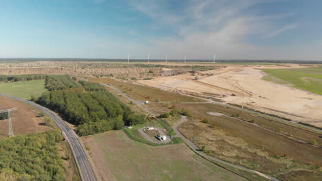 Industrial-brown-coal-lignite-mining-pit,-wind-turbines-in-background,-aerial