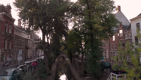 Backward-aerial-early-morning-canal-view-of-the-Nieuwe-Gracht-in-medieval-Dutch-city-of-Utrecht-just-above-upper-street-level-revealing-bikes-parked-on-the-bridge-in-the-foreground