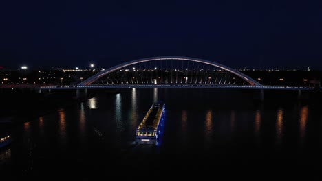 Toma-Aérea-Nocturna-De-Un-Moderno-Puente-Apolo-A-Través-Del-Río-Danubio-En-Bratislava,-Eslovaquia