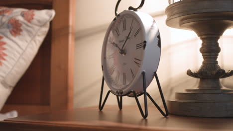 Sliding-shot-of-trendy-retro-vintage-clock-sitting-next-to-bed-on-nightstand