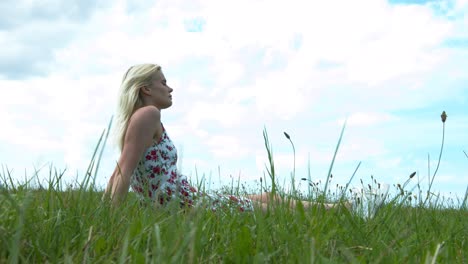 Woman-daydreaming-on-a-field-on-the-grass-in-a-gentle-breeze-of-wind