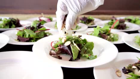 Salat-In-Einer-Ersten-Kameraebene-Und-Eine-Hand,-Die-Gehackte-Mandeln-Einlegt