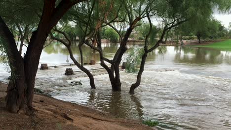 Floodwaters-flow-over-the-walking-bridge-at-Indian-Bend-Wash-Scottsdale,-Arizona
