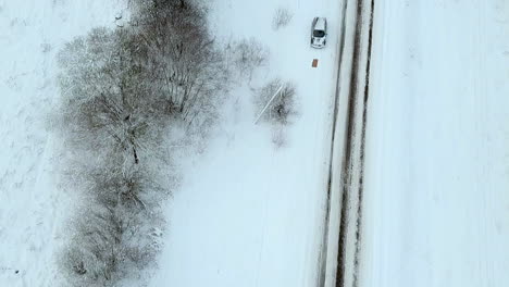 Aerial-flying-over-road-in-white-snow-on-overcast-day