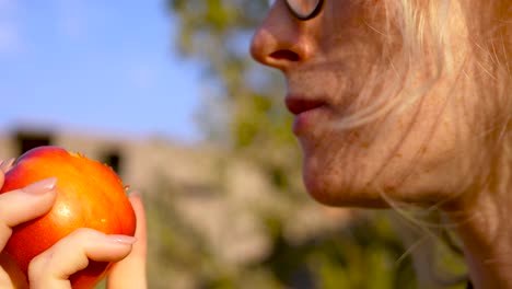 close-up-shot-of-young-woman-taking-a-bite-of-a-peach