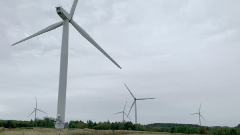 Windturbinen,-Die-Sich-An-Einem-Bewölkten-Tag-In-Einem-Windpark-In-Northumberland-Drehen,-Von-Hinten-Geschossen