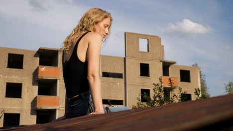 slow-motion-of-a-skinny-blond-woman-model-sitting-on-the-edge-of-concrete-wall-and-thoughtfully-looking-to-the-ground