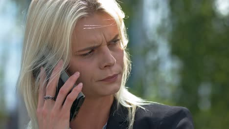 Static-close-up-slow-motion-shot-of-a-sad-blonde-lady-talking-on-the-phone-and-almost-crying