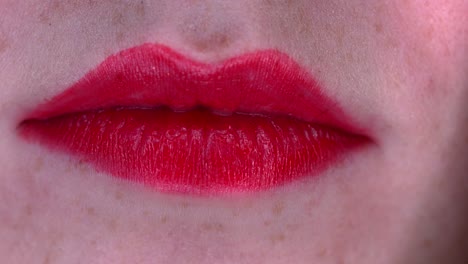 Closeup-view-of-lips-with-red-lipstick-of-a-young-woman-opening-up-to-expose-her-beautiful-smile