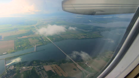 Through-airplane-window-view,-aircraft,-plane-window,-aerial-sky,-clouds,-river-view,-during-flight-plane-seat-view-looking-through-the-window