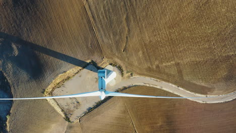 reverse-aerial-view-amazing-flight-flying-over-wind-turbine-tilting-camera-to-get-a-stunning-view-of-renewable-energy-source-making-power-from-wind,-showing-the-scale-of-wind-farms-using-highway