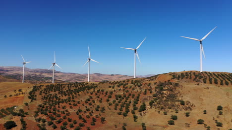 4k-aerial-view-of-5-wind-turbines-making-alternative-energy,-renewable-energy-source,-blue-sky-farm-lands