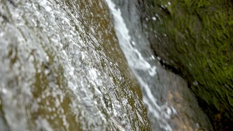 Closeup-of-small-waterfall-on-beach-cliffs,-slow-motion