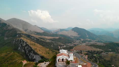 AERIAL-DOLLY-IN:-drone-flying-towards-a-typical-small-Italian-church-in-an-extreme-setup-on-top-of-an-isolated-hill-surrounded-by-an-incredible-view-of-mountains-in-south-of-Italy,-Maratea-Basilicata