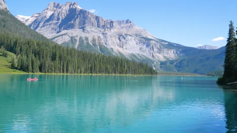 Vista-Natural-Del-Paisaje-Del-Lago-Esmeralda,-Parque-Nacional-Yoho,-Alberta,-Canadá-Con-Una-Canoa-En-El-Lago-Con-Un-Cielo-Azul-Claro-Y-Una-Cordillera-Rocosa-En-Verano-Durante-El-Día