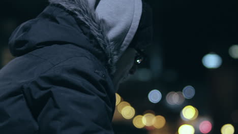 Hooded-man-with-glasses-looks-out-over-the-city-on-a-cold-night