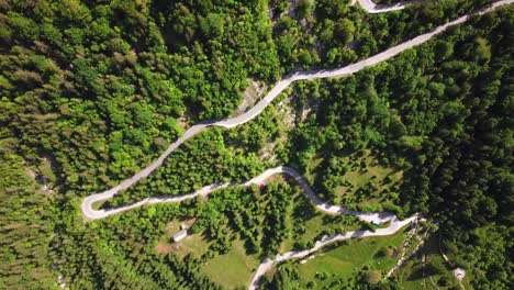 Drone-shot,-top-view,-of-a-slovenian-country-road-surrounded-by-a-mountain-forest