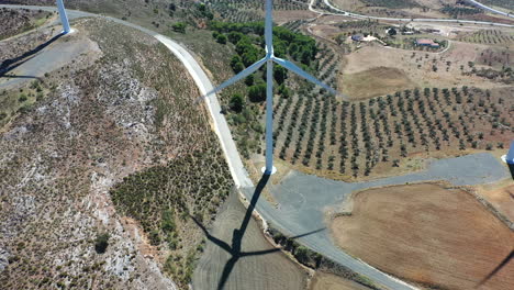 Aerial-view-of-wind-turbines-casting-shadows-on-the-ground,-alternative-renewable-energy-source-generating-electrical-power-for-natural-wind-movement