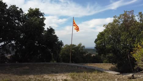 Bandera-Catalana-En-La-Cima-De-Una-Colina,-Con-Vistas-A-Las-Colinas-Con-Un-Cielo-Nublado