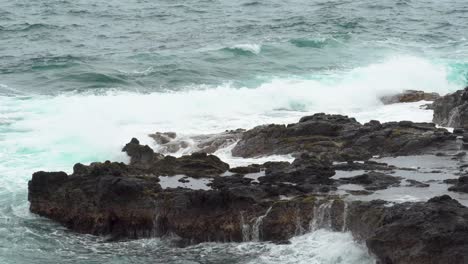Rough-waves-crash-against-jagged-rocks-near-Queen's-Bath,-Kauai,-Hawaii
