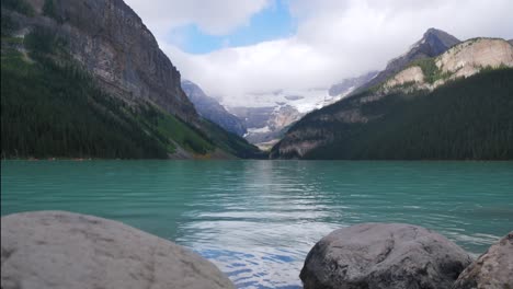 Zeitraffer-Landschaftsansicht-Des-Lake-Louise---Einer-Der-Berühmtesten-Seen-Im-Banff-Nationalpark,-Alberta,-Kanada---Im-Sommer-Tagsüber-Nach-Regen-Mit-Wolken-Am-Himmel-Und-Menschen,-Die-Im-See-Kanu-Fahren