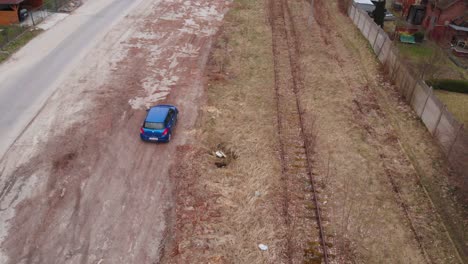 A-blue-car-drives-along-neglected-railway-tracks
