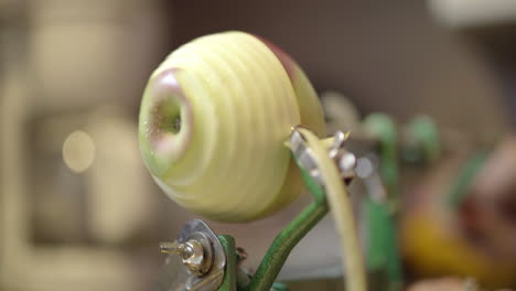 Close-up-of-a-manual-apple-peeler-skinning-the-peel-from-an-apple