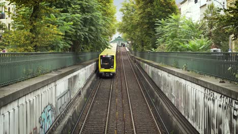 Yellow-underground-train-in-daylight-of-Berlin-and-on-rails-driving-into-tunnel