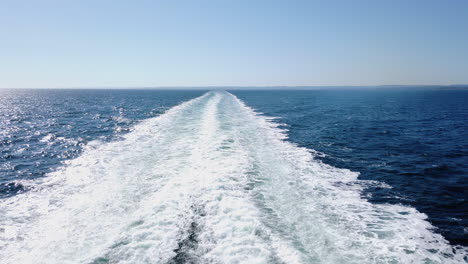 Pov-shot-backwards-of-waves-coming-from-a-moving-car-ferry,-on-the-Skagerrak-ocean,-heading-towards-Denmark,-from-South-Norway,-on-a-sunny-summer-day