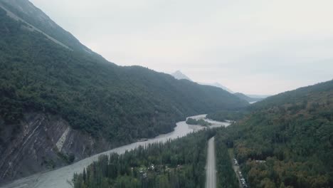 Aerial-view,-drone-flight-along-the-Glenn-Highway-and-the-Matanuska-River-in-the-Chugach-Mountain-Range-of-central-Alaska-on-a-cloudy-summer-day