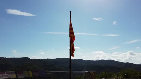 Zoom-in-on-Catalan-flag-barely-moving-on-top-of-a-hill,-overlooking-hills-with-a-cloudy-sky