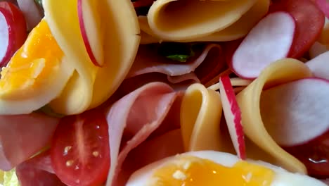 Colorful-family-food-platter-made-of-vegetables,-soft-boiled-eggs,-salami,-and-cheese,-SLIDE-ALONG
