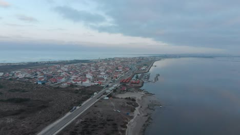 Aerial-view-of-a-small-village-between-the-ocean-and-the-river-on-a-cloudy-day
