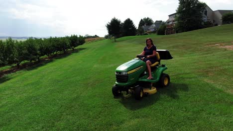 Young-hispanic-woman-mowing-lawn-on-tractor-cutter