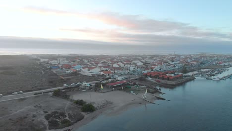 Aerial-view-during-sunset-of-a-small-village-between-the-ocean-and-the-river