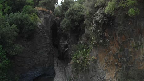 4K-AERIAL:-Drone-descending-above-Alcantara-Gorges,-an-impressive-channel-of-lava-columns-eroded-naturally-into-ravines,-canyons-and-caves