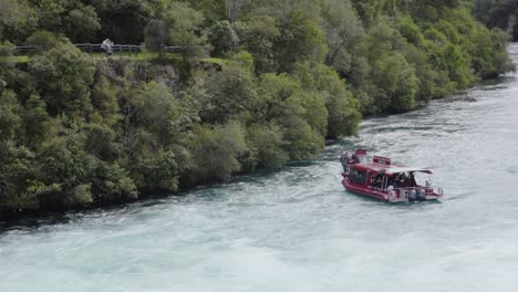 A-zoomed-in-shot-of-the-Huka-Falls-cruise-boat-maneuvering-in-the-water-with-people-watching-from-a-lookout
