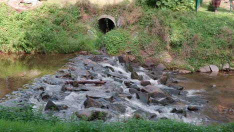 Sewage-pipe-outflow-into-river,-water-pollution-and-ecology-concept,-urban-wastewater-system