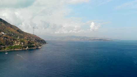 AERIAL:-Drone-flying-above-the-Tyrrhenian-Sea,-with-an-incredible-view-of-Sicily's-coast-from-Calabria,-Italy
