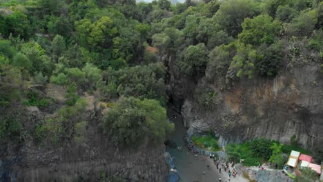 4K-AERIAL:-Drone-rising-above-Alcantara-Gorges,-an-impressive-channel-of-lava-columns-eroded-naturally-into-ravines,-canyons-and-caves