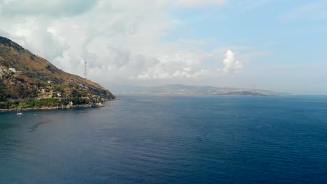 AERIAL:-Drone-flying-above-the-Tyrrhenian-Sea,-with-an-incredible-view-of-Sicily's-coast-from-Calabria,-Italy