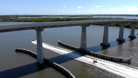 Aerial-drone-shot-of-a-jetski-going-under-a-causeway-on-the-Indian-River-Lagoon-in-Sebastian-FL