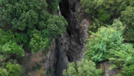 4K-AERIAL-TILT-DOWN:-Drone-flying-above-Alcantara-Gorges,-an-impressive-channel-of-lava-columns-eroded-naturally-into-ravines,-canyons-and-caves