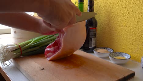 Male-hands-cutting-skin-from-pork-belly-piece-in-home-kitchen-setting