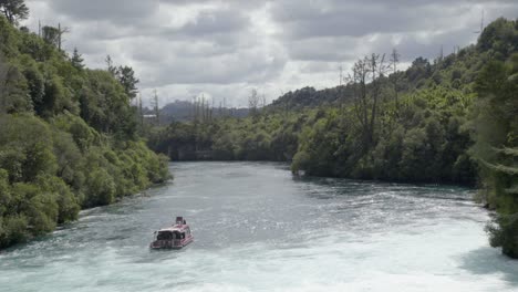 A-wide-shot-looking-down-the-Waikato-river-as-the-Huka-Falls-cruise-boat-floats-just-downstream-from-the-Huka-Falls-in-Taupo,-NZ