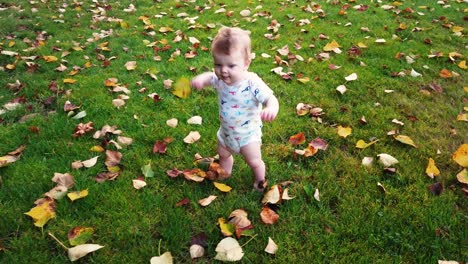 Happy-toddler-takes-first-steps-unassisted-in-grass-field-full-of-leaves